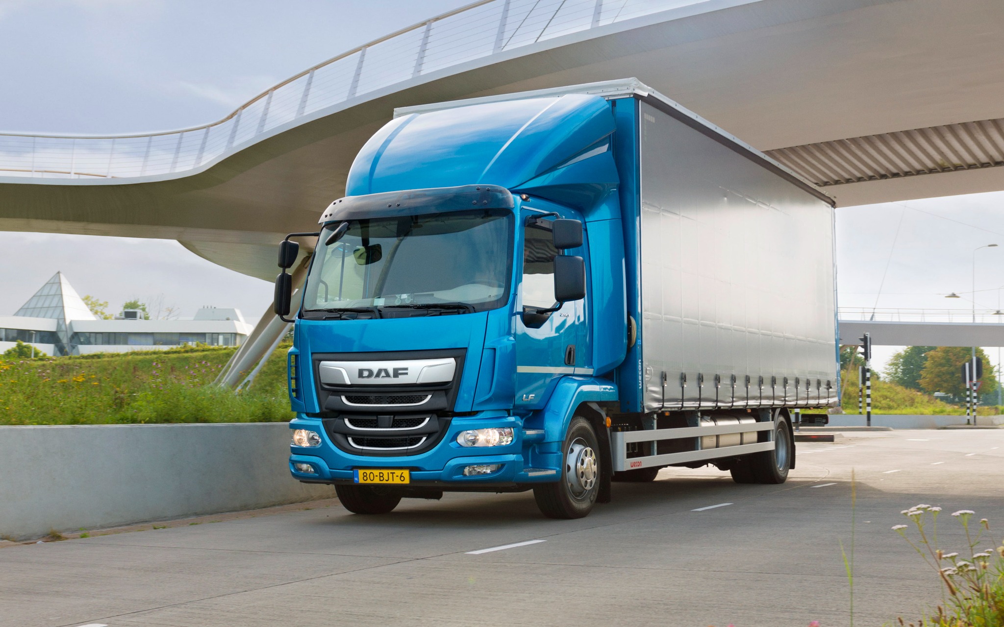 Blue distribution truck with a covered cargo body on the road