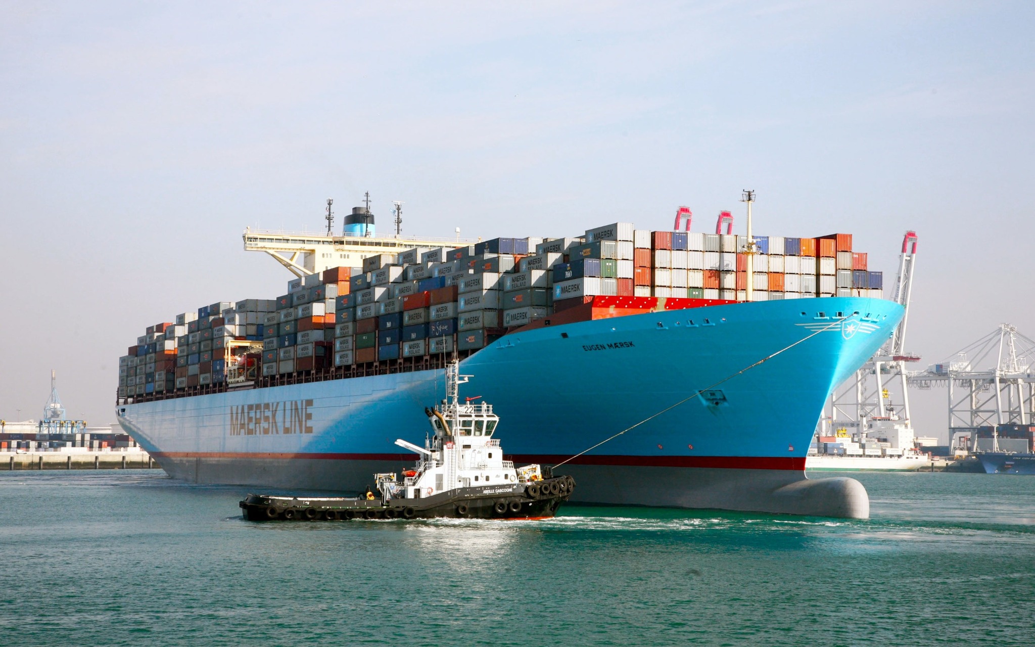 Blue container ship and tugboat at a cargo port